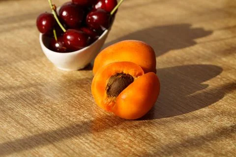 Ripe apricots are lying on the table, with a pitted seed visible Stock Photos