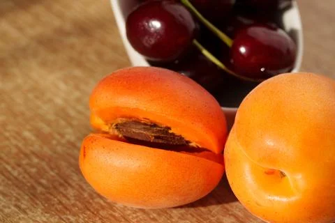 Ripe apricots are lying on the table, with a pitted seed visible Stock Photos