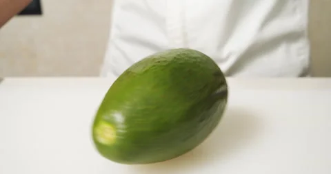 Ripe avocado fruit rotating on the table. Male chef hands taking an avocado Stock Footage 135494878