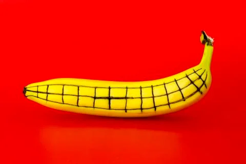 Ripe banana with a pattern on its side on a red background Stock Photos