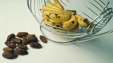 Ripe Bananas and Dates on White Surface, A cluster of ripe yellow bananas w.. Vídeo Stock 304974440