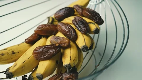 Ripe Bananas and Dates in Wire Basket, A wire fruit basket containing ripe .. Vídeo Stock 304975000