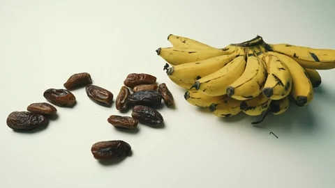 Ripe Bananas and Dried Dates on White Surface Footage, A bunch of ripe bana.. 動画素材 304974090