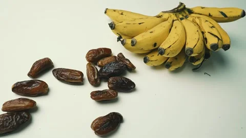 Ripe Bananas and Dried Dates on White Surface Footage, A bunch of ripe bana.. Видео 304974131