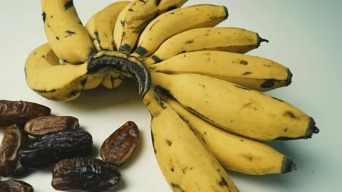 Ripe Bananas and Dried Dates on White Surface, A bunch of ripe bananas next.. 動画素材 304974266
