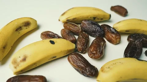 Ripe Bananas and Dried Dates on White Surface, A close-up of ripe bananas a.. 動画素材 304975080