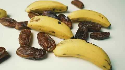 Ripe Bananas and Dried Dates on White Surface, A close-up of ripe bananas a.. 動画素材 304975130