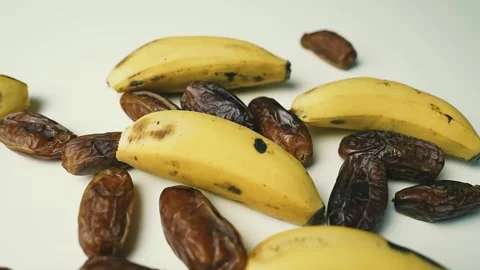 Ripe Bananas and Dried Dates on White Surface, A close-up of ripe bananas a.. Stockbeeldmateriaal 304975155