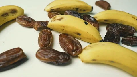 Ripe Bananas and Dried Dates on White Surface, A close-up of ripe bananas a.. Video stock 304975183