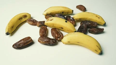 Ripe Bananas and Dried Dates on White Surface, A collection of ripe bananas.. Stockbeeldmateriaal 304977411