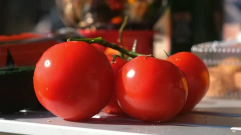 Ripe big tomatoes on table in picnic on nature at sun with drops of water. Stock Footage 277868983