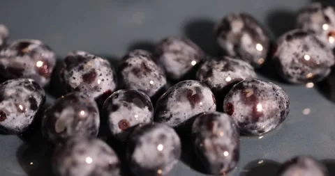 A ripe blue grape torn from a branch, lying on a bowl, covered with drops of Stock Footage 319620732