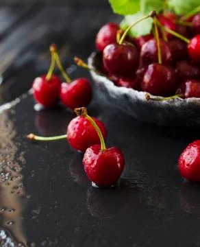 Ripe cherries or cherry with drops of water on black stone Stock Photos