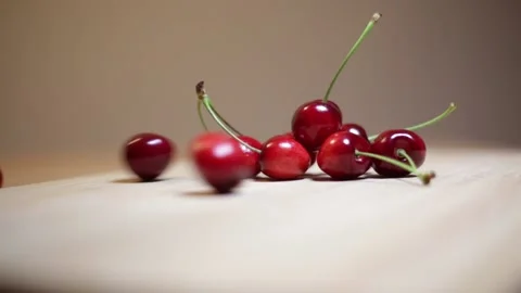 Ripe cherries rolling across table with few cherries in the backdrop Stock Footage