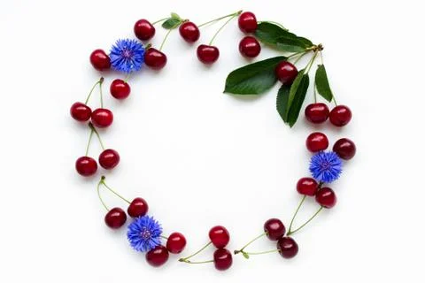 Ripe cherry lined in shape of frame with green leaves, decorated with flowers. Stock Photos