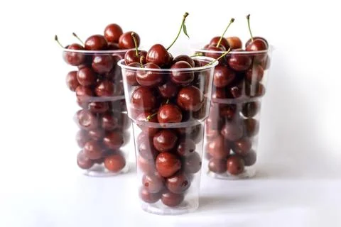 Ripe cherry in a plastic cup on a white background. Stock Photos