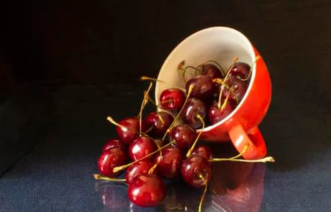 Ripe cherry in red cup on table Stock Photos