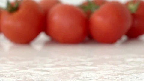 Ripe cherry tomatoes roll on a white mirror surface against a background of Stock Footage 92857805