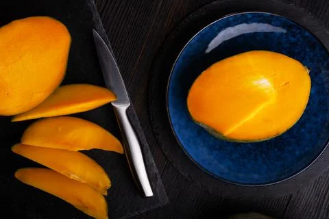 Ripe egyption Mango slices served  at black dish and blue plate. close up Stock-Fotos