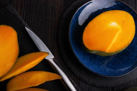 Ripe egyption Mango slices served on  plate at black table. close up Stock Photos