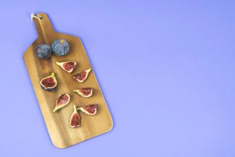 Ripe figs cut on a kitchen table on a blue background. Copy space. Stock Photos