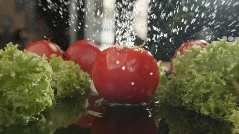 Ripe fresh tomato drops on table with water with spray in slow motion Stock Footage 117335777