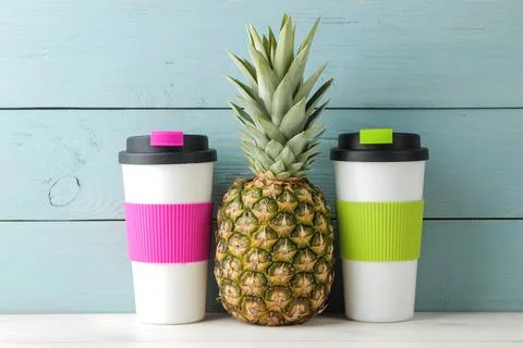 Ripe fruit pineapple and plastic thermoglass on a blue wooden background. sum Stock Photos