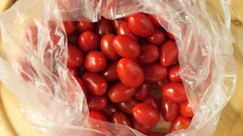 Ripe grape tomatoes rotating inside a plastic bag Video stock 335837129