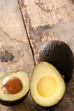 Ripe halved avocado pear on a rustic table Stock Photos