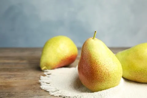 Ripe juicy pears on brown wooden table against blue background. Space for tex Stock Photos
