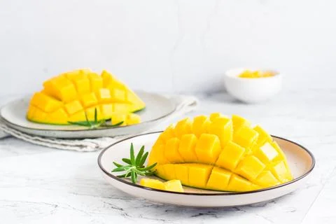Ripe mango cubes on plates on the table. Tropical fruit Stock Photos
