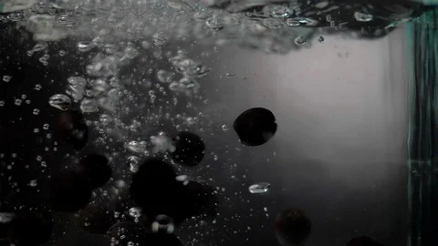 Ripe olives fall into crystal clear water. Dark Food. Super slow motion Stock Footage 89368614