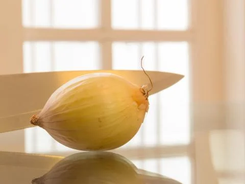 A ripe onion and knife reflected on white background Foto stock