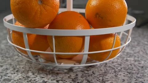 Ripe oranges sits in a fruit basket on kitchen counter, tilt up shot on orang Video stock 154435059