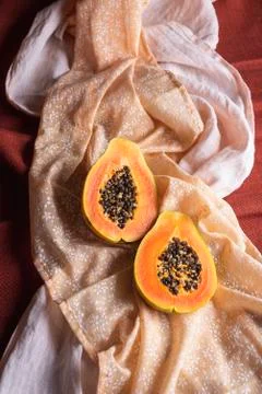 Ripe papaya fruit halves on orange shades tablecloths. Summer fruit Stock Photos
