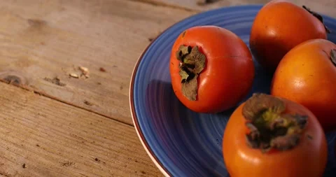 Ripe Persimmons on a Blue Plate. Stock Footage 260341818