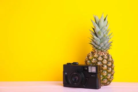 Ripe pineapple with camera on a yellow background Stock Photos