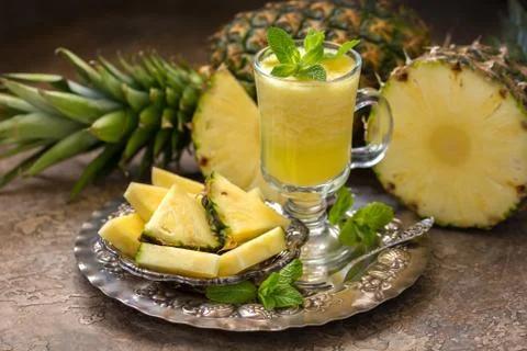 Ripe pineapples (Ananas comosus) and a glass of fresh juice on a vintage dish Stock Photos