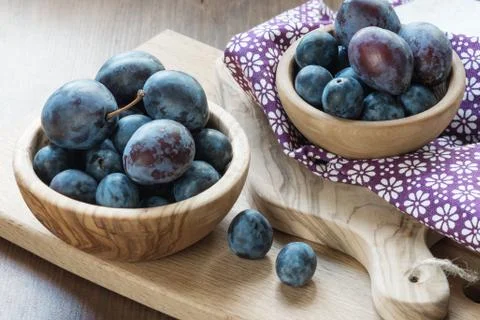Ripe plums in the wooden bowls Stock Photos