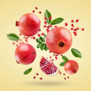 A ripe pomegranate with seeds and leaves flying in the air. Background with Stock Photos