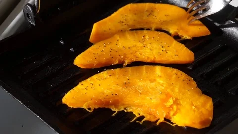 Ripe pumpkin pieces roasting on the grill pan Stock Footage 72725866