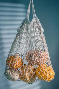 Ripe pumpkins in mesh bag with creative light. Eco-friendly farm products. Au Stock Photos