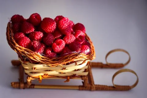 Ripe raspberry berries are folded into a wicker basket that is shaped like a  Foto stock