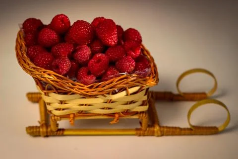 Ripe raspberry berries are folded into a wicker basket that is shaped like a  Stock Photos