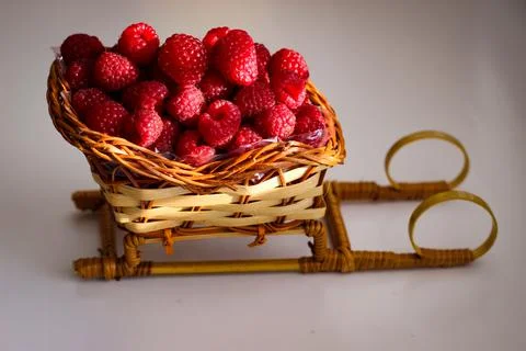Ripe raspberry berries are folded into a wicker basket that is shaped like a  Stock Photos