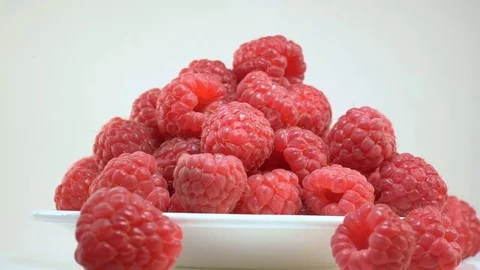 A ripe raspberry is lying on a white plate Stock Footage 77715189