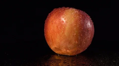 Ripe red apple on a mirror background. A red apple rotates on a wet mirror. F Stock Footage 92347601