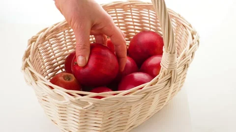 Ripe red apple in wicker basket isolated on white. A man bites off a piece of an Stock Footage 239298583