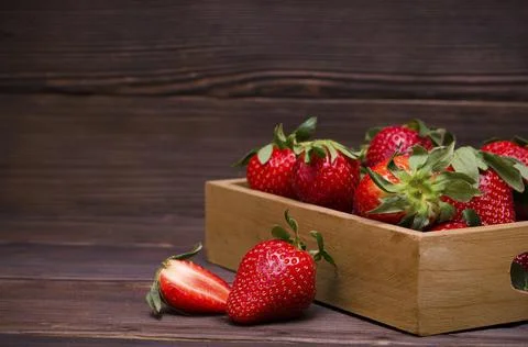 Ripe red berries strawberries in a box on a wooden background Stock Photos