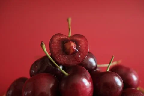 Ripe red cherries with cut cherry on red background Stock Photos